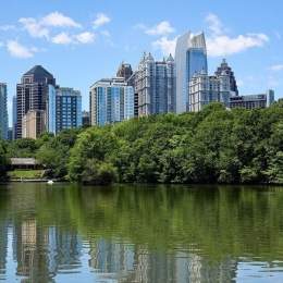 a body of water reflecting trees and skyscrappers